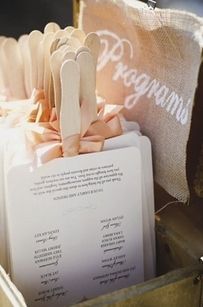 there is a wedding program in a box with clothes pins attached to the file folders