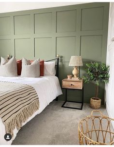 a bedroom with green paneled walls and a bed in the corner, next to a wicker basket