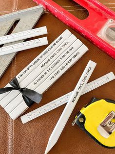 several rulers and tape measures on top of a piece of brown leather next to a red ruler