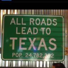 a green sign that says all roads lead to texas