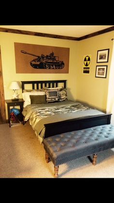 a bedroom with a bed, ottoman and pictures on the wall above it is shown