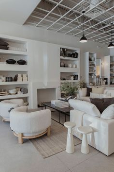 a living room filled with white furniture and lots of shelves