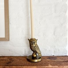 an owl figurine sitting on top of a wooden table next to a candle