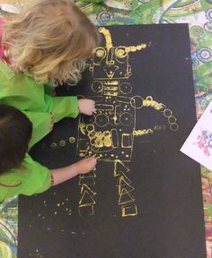 a young child is drawing on a black piece of paper with gold foil and colored crayons