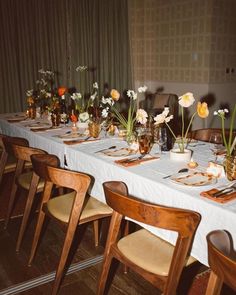 a long table is set with flowers in vases and place settings for the dinner guests