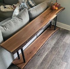 a living room with couches, pillows and a wooden shelf on the floor in front of it