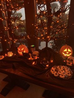 a table with pumpkins and other halloween decorations on it, in front of a window