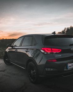 the back end of a gray car parked on a dirt road