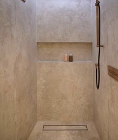 a bathroom with a shower head, shelf and candles on the wall next to it