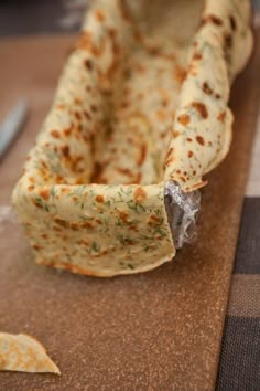 a tortilla sitting on top of a wooden cutting board next to a knife