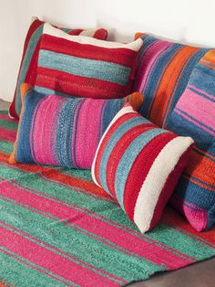 multicolored striped pillows on top of a bed