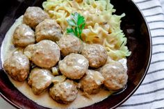 meatballs, pasta and sauce in a bowl on a tablecloth with a fork