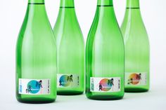 three green bottles with stickers on them are lined up in front of each other