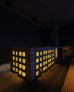 an empty room with a counter, stools and lights on the floor in front of it