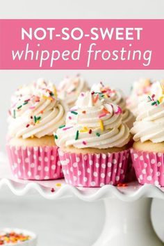 cupcakes with white frosting and sprinkles are on a cake plate