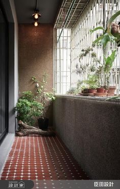 an indoor balcony with potted plants on the wall and tiled flooring, along with brick walls