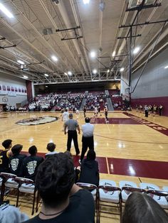 an indoor basketball court with people sitting in chairs and watching the game from the sidelines