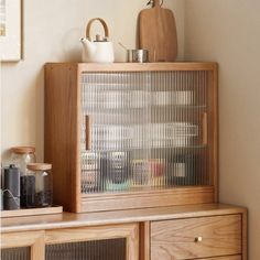 a wooden cabinet with glass doors and drawers on top of it, in front of a white wall