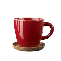 a red coffee cup sitting on top of a wooden plate