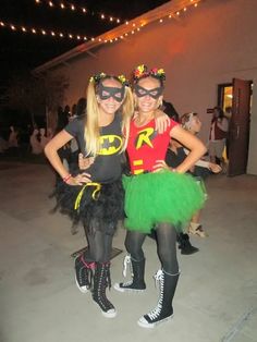 two women dressed up as batman and robinette in costumes at a party with people sitting around