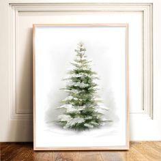 a white christmas tree with snow on the branches in front of a framed wall hanging