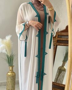 Are you looking for an elegant and traditional outfit for the summer? The Moroccan summer jellaba is perfect with its lightweight fabric and fine embroidery. If you like sets, the embroidered 2-piece djellaba is ideal with its intricate details. For a modest yet chic look, go for the hooded caftan. Each Moroccan dress you wear tells a part of the cultural history of the Arab world. For a special occasion like an Islamic wedding, nothing beats the Nikah dress, richly adorned. The hooded Moroccan Summer Wedding Long Abaya, Traditional Summer Wedding Abaya, Traditional Maxi Length Abaya For Summer, Traditional Maxi-length Kimono For Eid, Traditional Summer Maxi Length Abaya, Traditional Maxi Length Summer Abaya, Traditional Maxi-length Summer Abaya, Traditional Long Abaya For Summer, Long Kaftan With Embroidered Border For Eid