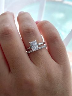 a woman's hand with a diamond ring on top of her finger and an engagement band