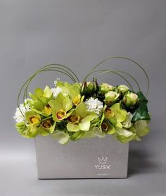 an arrangement of flowers in a silver box