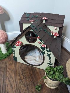 a dog house made out of cardboard with mushrooms on the roof and grass around it