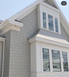 a white house with gray shingles and windows