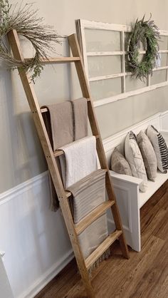 a ladder leaning up against a wall next to pillows and wreaths on the ledge