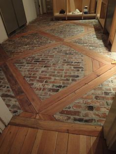 an old brick floor in a kitchen with wood trimmings on the top and bottom