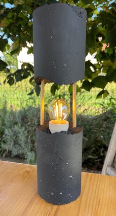 a light that is sitting on top of a wooden table in front of some trees