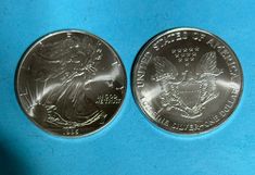 two american silver eagle coins on a blue background