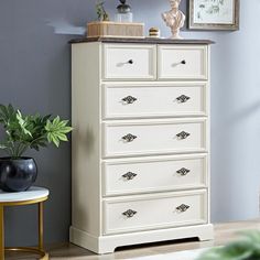 a white dresser sitting next to a potted plant