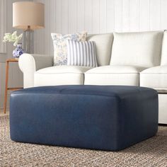 a living room with white couches and blue ottoman