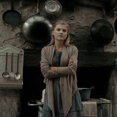 a woman standing in front of pots and pans