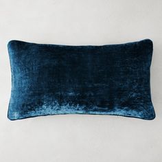 a blue velvet pillow on a white wall