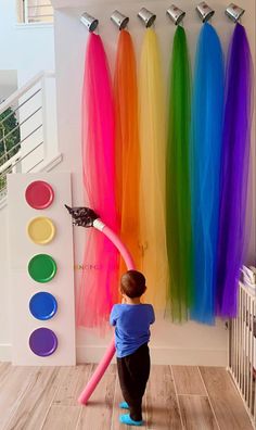 a little boy that is standing in front of a wall with some colored hair on it