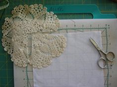 two pieces of white lace on top of a cutting board next to scissors and tape