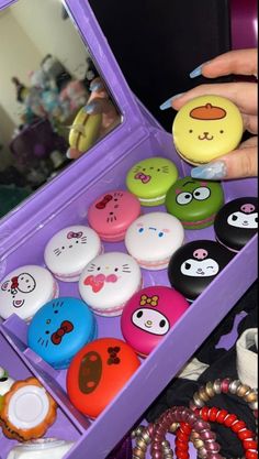 a person holding an open purple box filled with lots of different colored buttons and bracelets