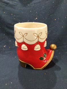 a red and white ceramic cup with bells on the bottom is sitting on a blue surface