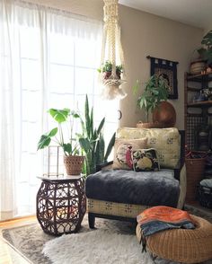 a living room filled with lots of plants next to a couch and ottoman on top of a rug