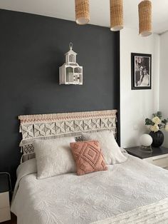 a white bed sitting in a bedroom next to two pictures hanging on the wall above it