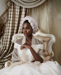 a woman in a white dress sitting on a bed wearing a turban and veil