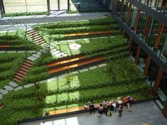 several people are walking around in front of a building with grass growing on the walls