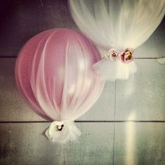 two balloons with white tulle and pink flowers on the top one has a large balloon attached to it's side