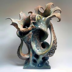 an octopus sculpture sitting on top of a blue base with its mouth open and eyes closed