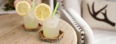 two glasses filled with lemonade sitting on top of a wooden table next to deer antlers