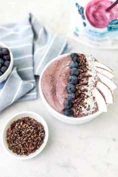 two bowls filled with blueberries and ice cream on top of a white marble counter